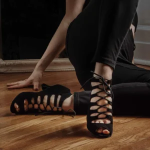 Femme portant des talons de danse noirs à lacets, bout ouvert, sur un plancher de bois